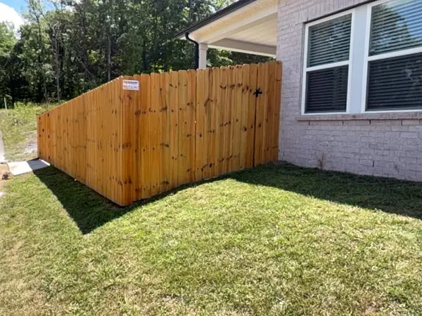 Stained wood privacy fence with a walk gate beside a brick house